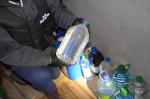 Funkcjonariusz KAS trzyma butelkę z nielegalnym alkoholem